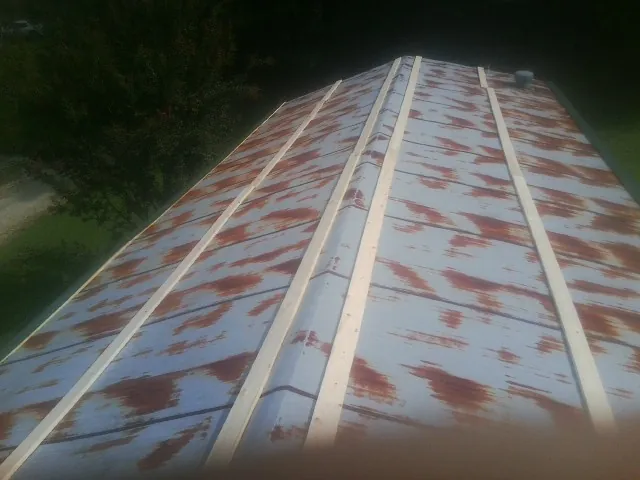 Rusted metal roof panels with new wood purlins before replacement — Storm Damage Roof Repair in Grain Valley by Roofing Brothers