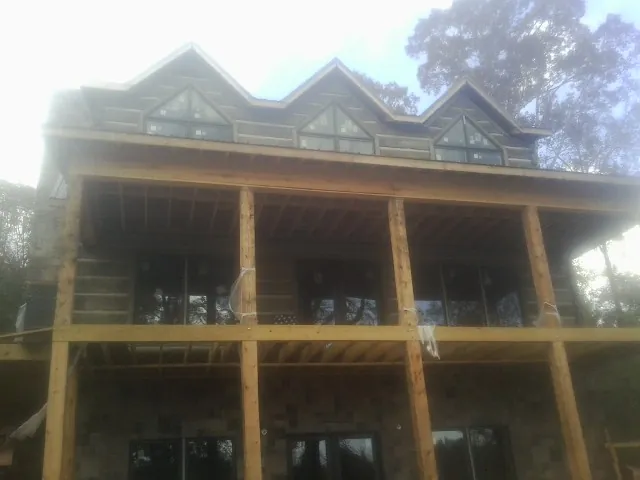 Dormers and porch framing on a large log home under construction — Roof Coating work by our crew in Grain Valley