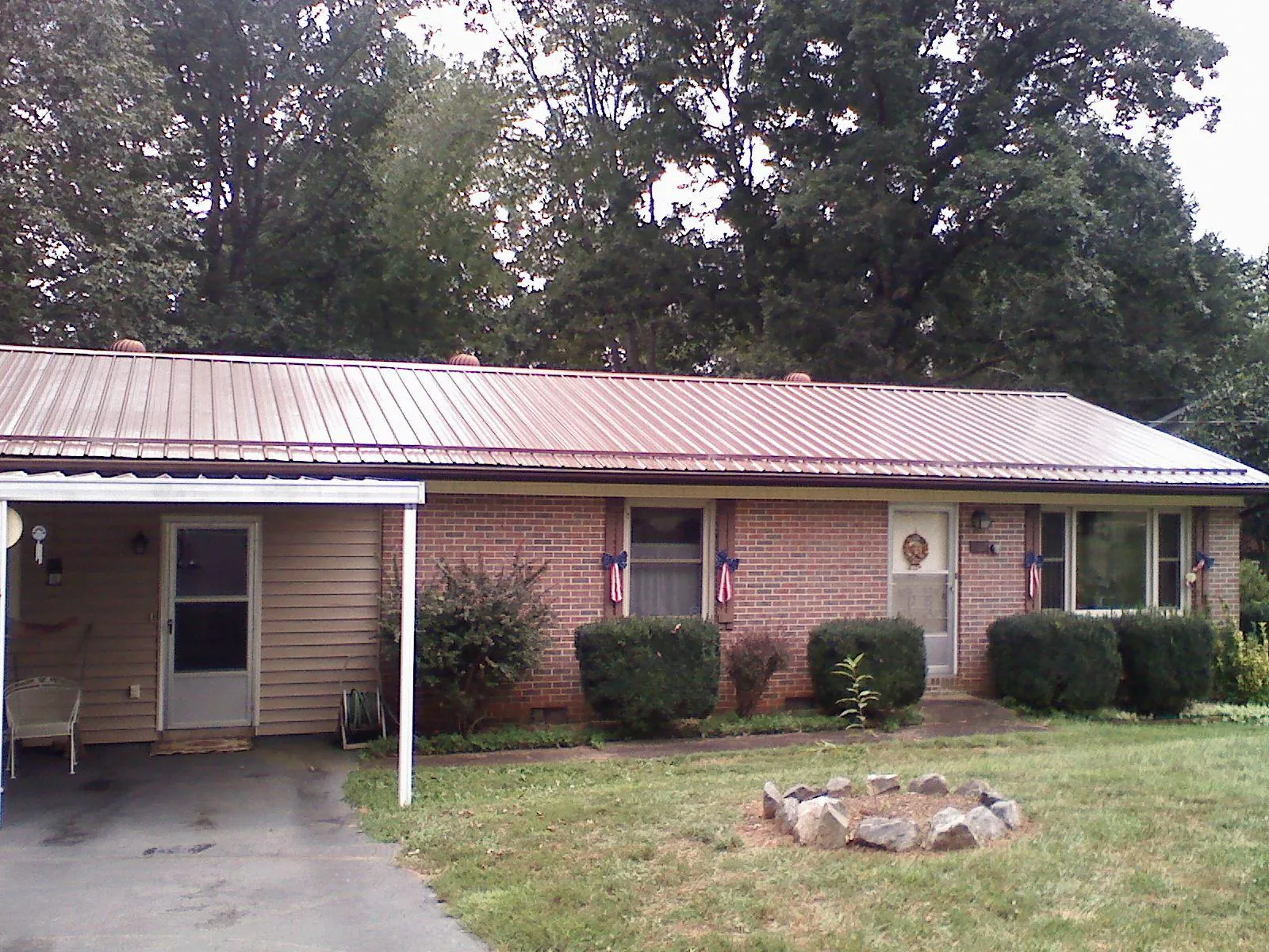 Bronze metal roof and carport on a brick ranch home — Roof Repair work by our crew in Grain Valley